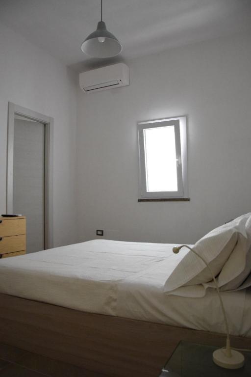 Ce lit se trouve dans un dortoir blanc doté d'une fenêtre. dans l'établissement L'Argonauta, à Lampedusa