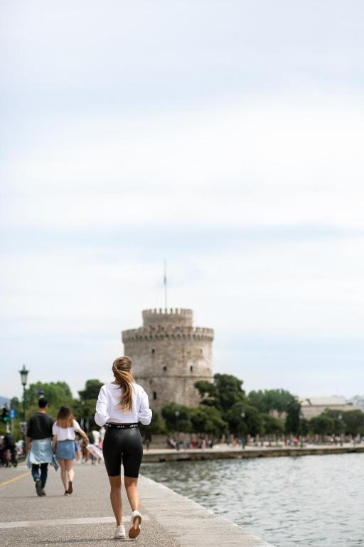 a woman walking down a sidewalk in front of a castle at Daios Luxury Living in Thessaloniki