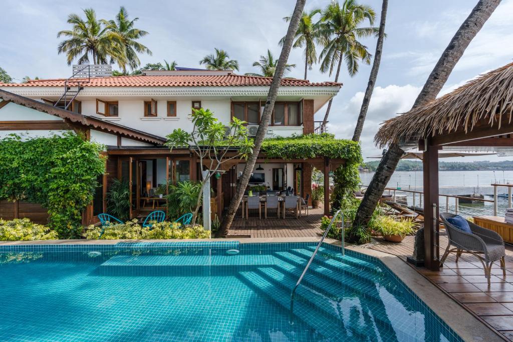 a villa with a swimming pool in front of a house at StayVista at Villa Kinara The Luxury Collection in Old Goa