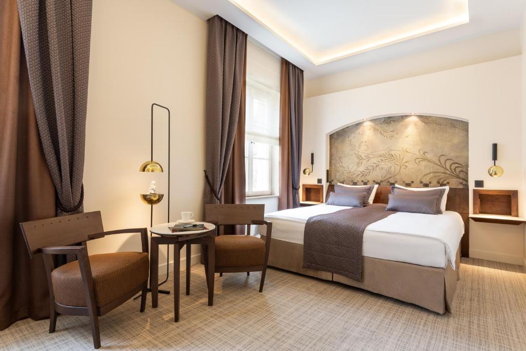 a hotel room with two beds and a table at Mamaison Le Regina Boutique Hotel in Warsaw