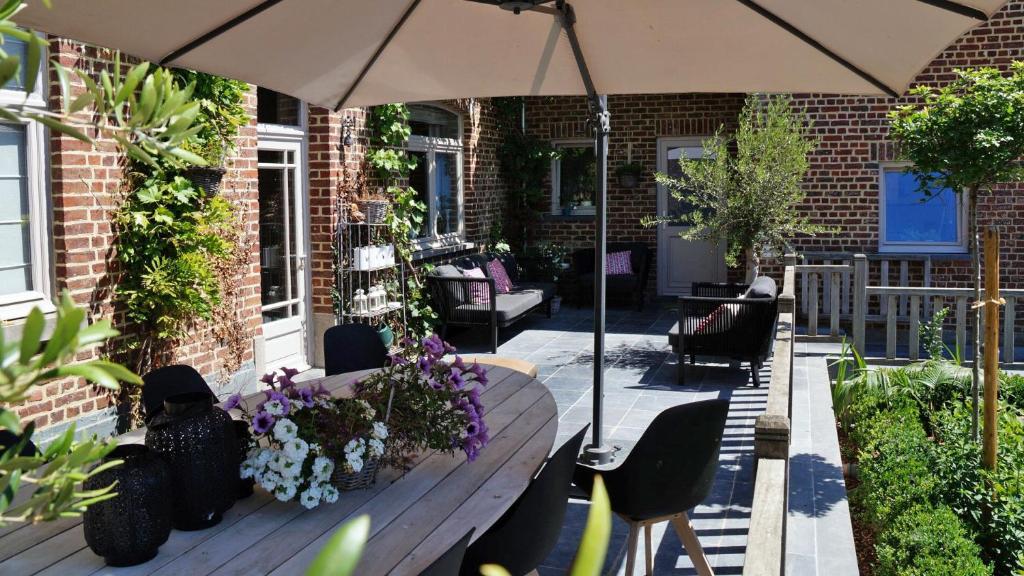 a patio with an umbrella and a bench with flowers at Guesthouse Biolleke in Boutersem