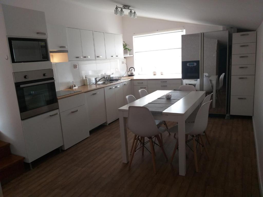 uma cozinha com armários brancos e uma mesa e cadeiras em Pokoje gościnne Venezia em Czaplinek