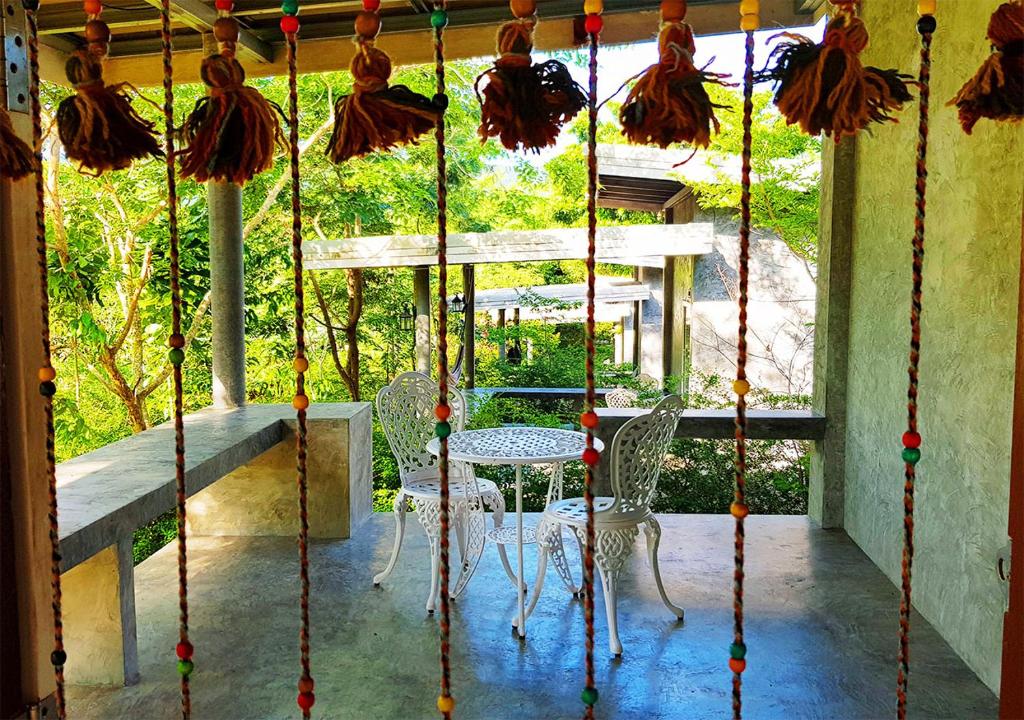 une terrasse couverte avec une table et des chaises. dans l'établissement New Moon, à Thongsala