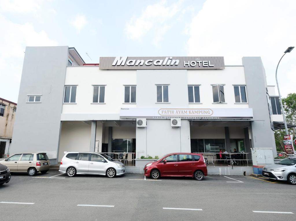 a white building with cars parked in a parking lot at Super OYO 43935 Mancalin Hotel in Kuantan