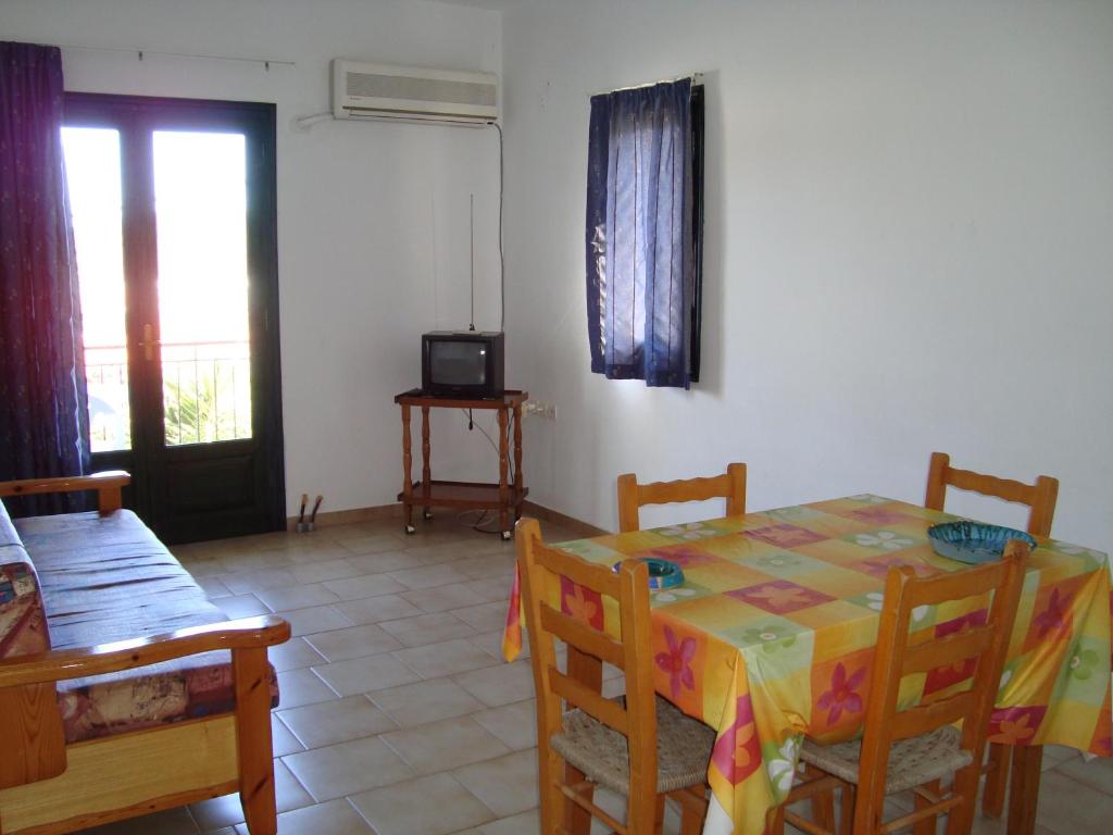 comedor con mesa, sillas y TV en Appartement 4 pers, en Palaia Epidavros