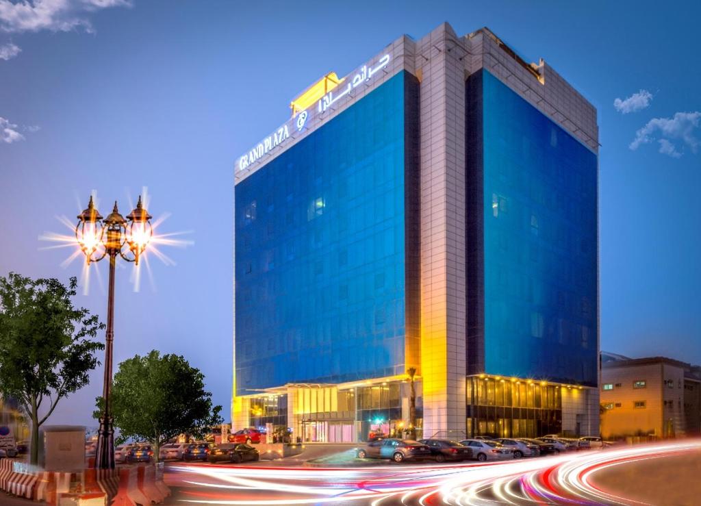 un grand bâtiment bleu avec des voitures devant lui dans l'établissement Grand Plaza Hotel - Gulf Riyadh, à Riyad