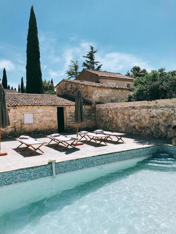une piscine avec chaises longues et parasols dans l'établissement Domaine de Carraire, à Aix-en-Provence
