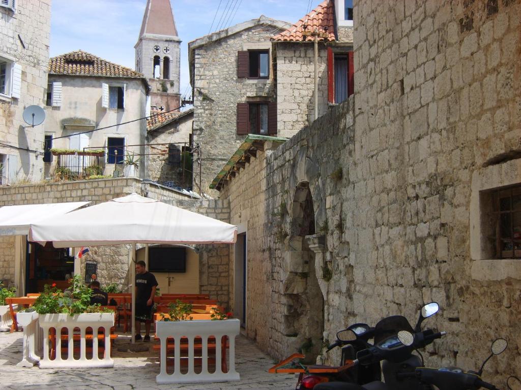 un homme debout sous un parapluie dans une allée dans l'établissement Rooms Roso, à Trogir