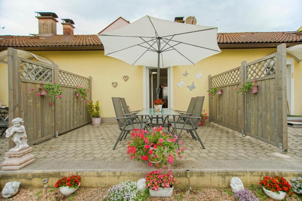 a patio with a table with an umbrella and flowers at Auszeit Leoben 3 mit Gartenterasse und Gratisparkplatz in Leoben