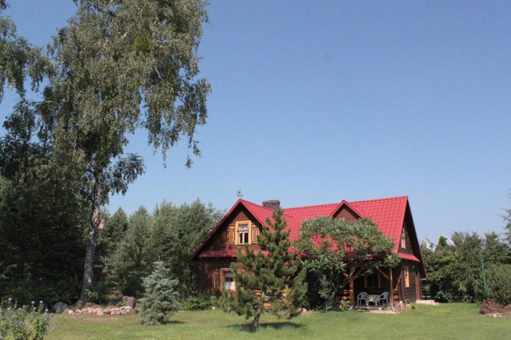 uma casa com um telhado vermelho num campo em Agroturystyka Ruta nad zalewem Siemianówka em Łuka