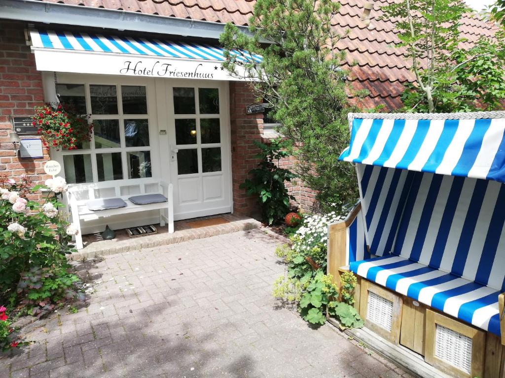 Hotel Garni Friesenhuus في غريتسيل: شرفة منزل مع مظلة زرقاء وبيضاء