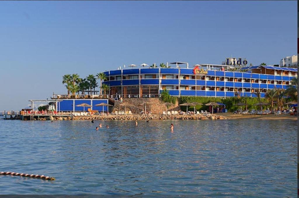 a hotel on a beach with people in the water at Lido Sharm Hotel Naama Bay in Sharm El Sheikh