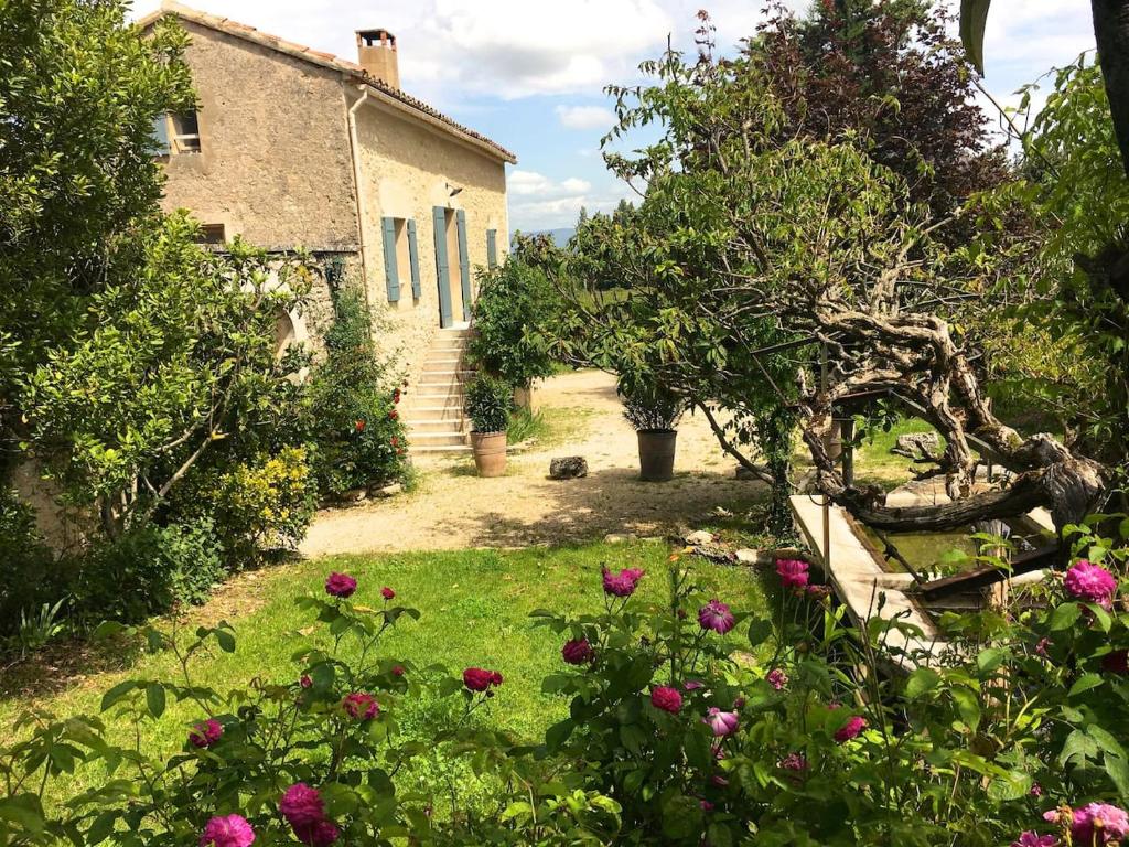 una casa antigua con un jardín con flores delante en La Magnanerie, en Bonnieux