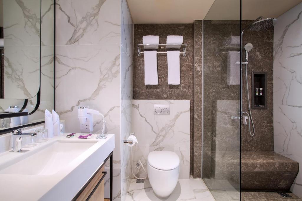 a bathroom with a toilet and a sink and a shower at Mercure Jakarta Batavia in Jakarta