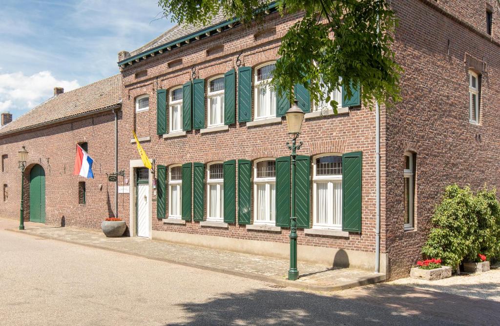 a brick building with green shuttered windows and a street light at B&B Woonboerderij Peters in Horn
