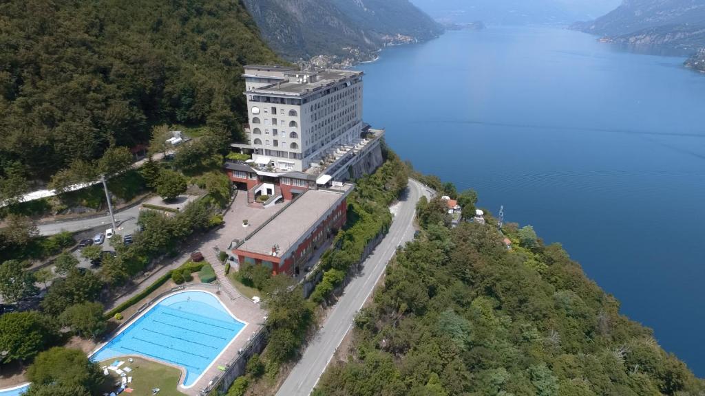 a building on top of a hill with a swimming pool at Kosmopolitan Residence in Valbrona