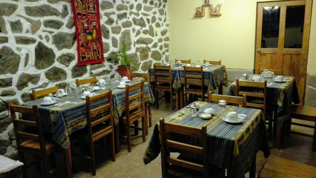 un restaurante con mesas y sillas y una pared de piedra en B&B Chayana Wasi, en Ollantaytambo