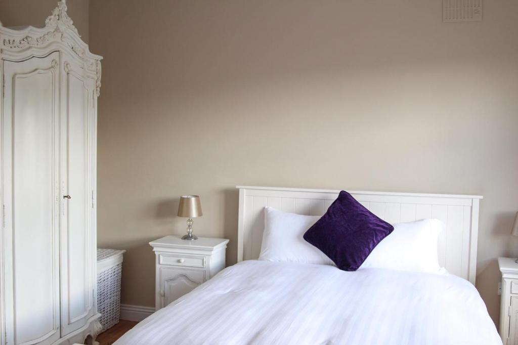 Una cama blanca con una almohada morada. en Atlantic Rose Cottage, en Doolin