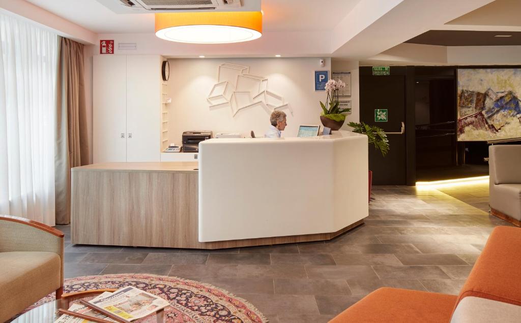 a woman standing at a reception desk in a lobby at Hotel Parma in San Sebastián