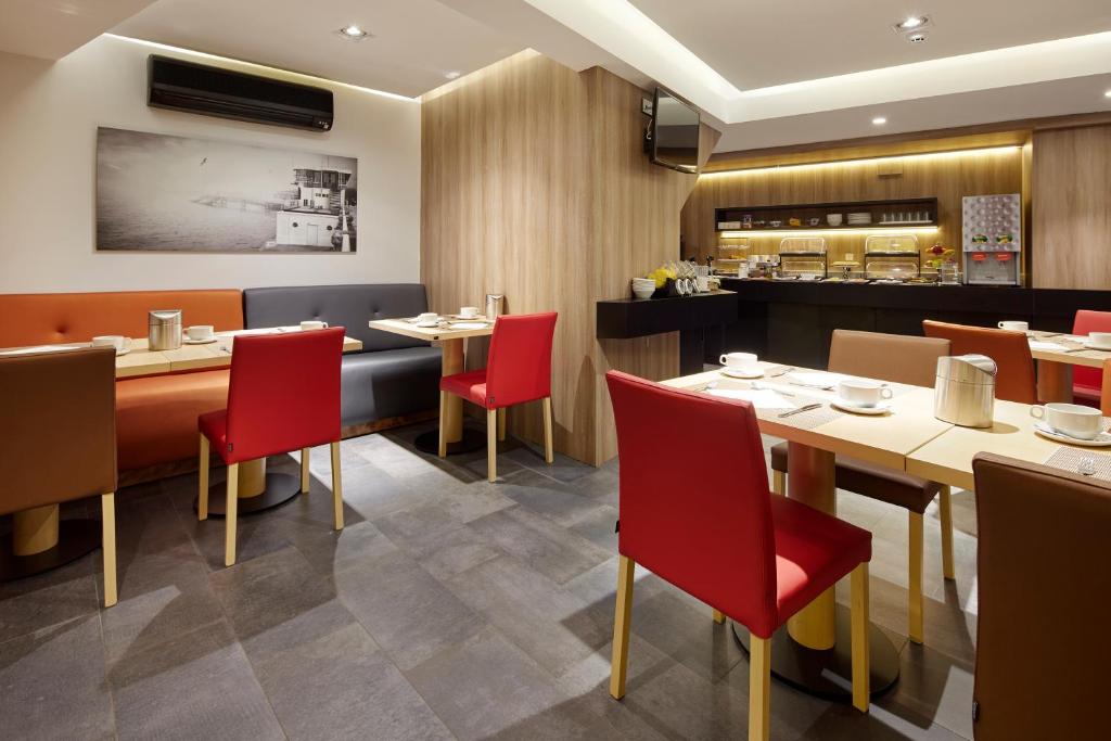 a restaurant with red chairs and tables and a kitchen at Hotel Parma in San Sebastián
