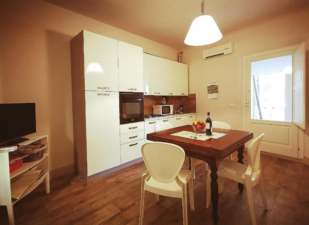 une cuisine avec une table, des armoires blanches et une télévision dans l'établissement Lanfranchi deluxe apartament, à Pise