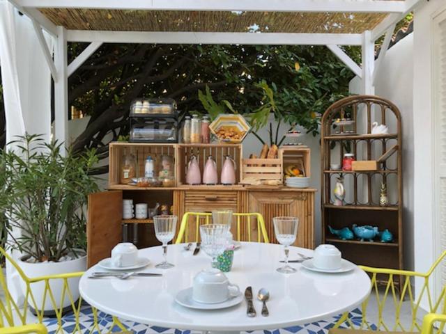 a white table with yellow chairs and a table with glasses at Hôtel Mademoiselle in Juan-les-Pins