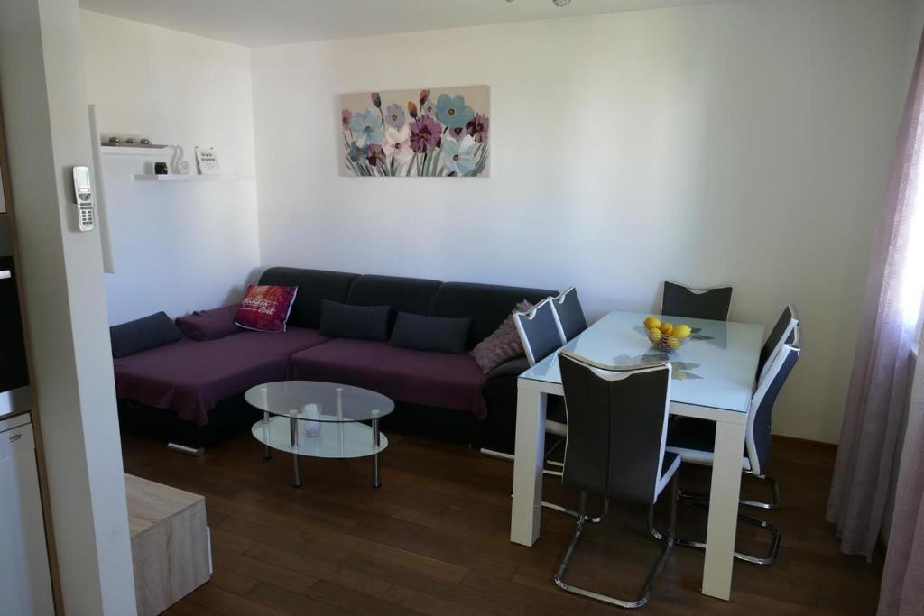 uma sala de estar com um sofá roxo e uma mesa em Heidi em Podstrana