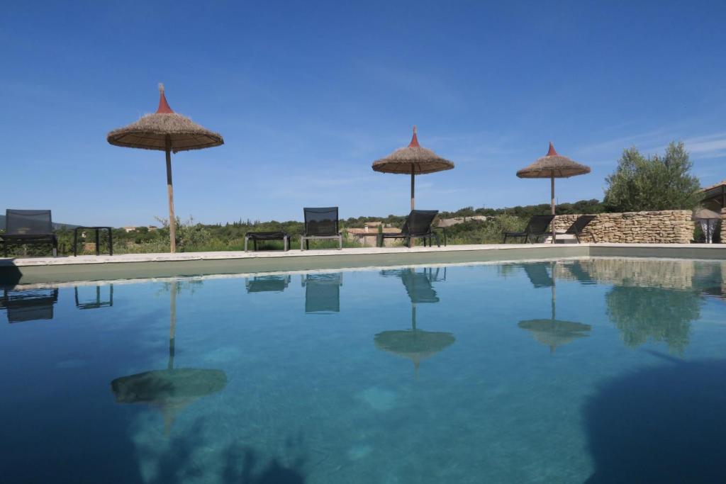 a swimming pool with chairs and umbrellas on top of it at Le Clos d'Estellan - Piscine chauffée in Bonnieux