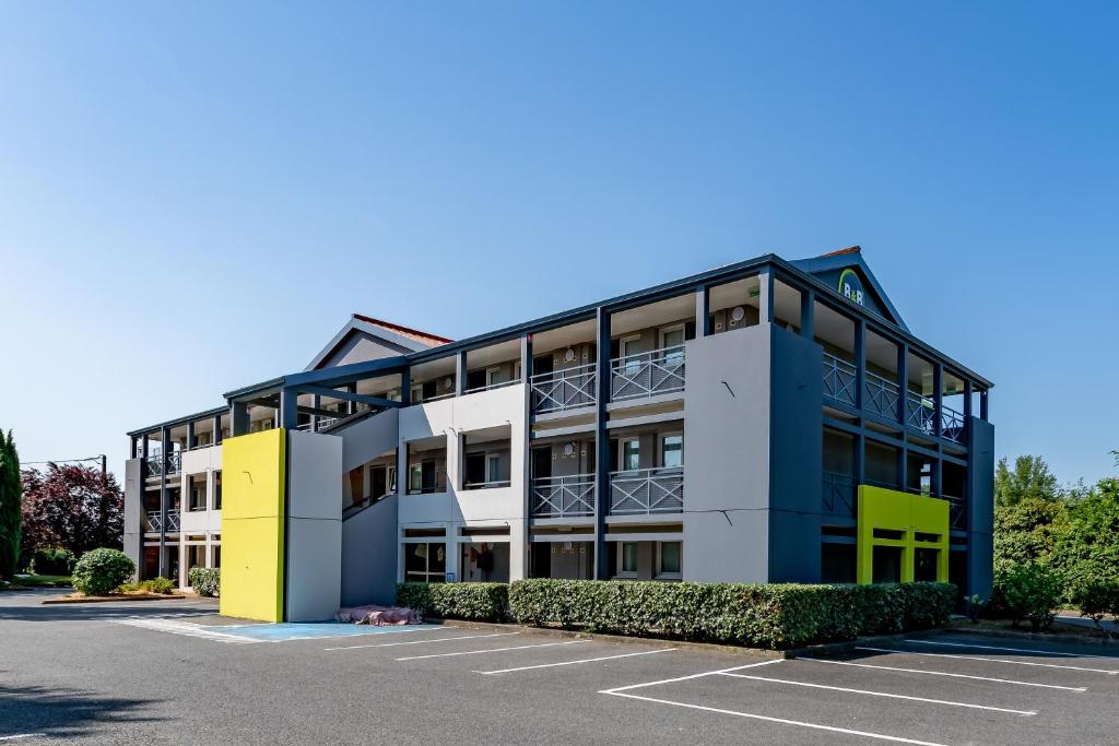 un edificio de oficinas con aparcamiento en B&B HOTEL Périgueux Boulazac en Boulazac