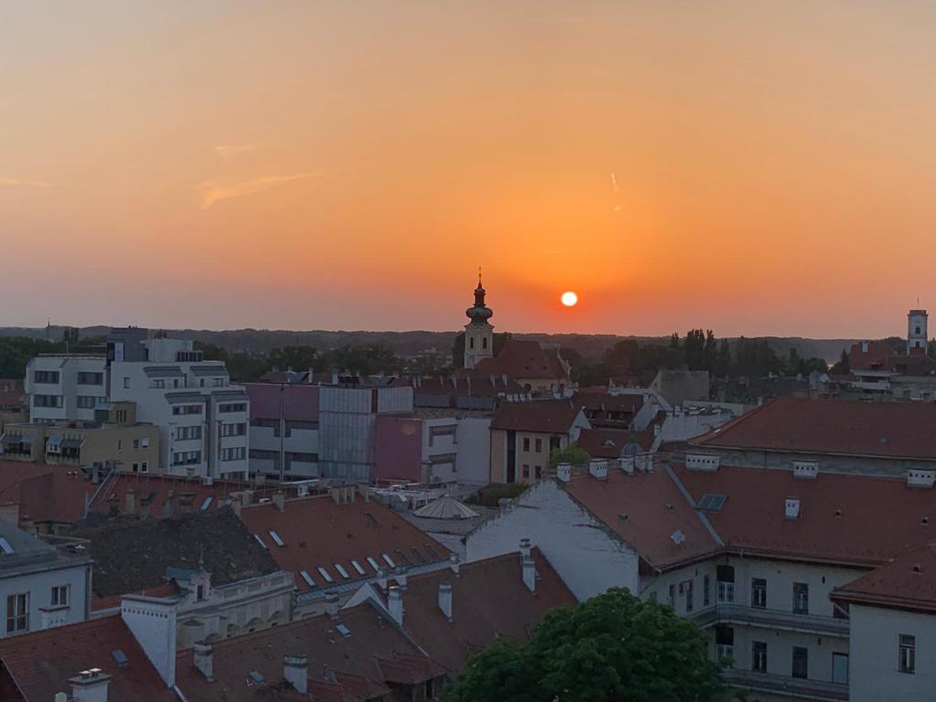 una puesta de sol sobre una ciudad con una torre de reloj en ORIGO en Győr