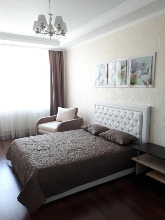 1 dormitorio con 1 cama grande y 1 silla en Альтаир1, en Odessa