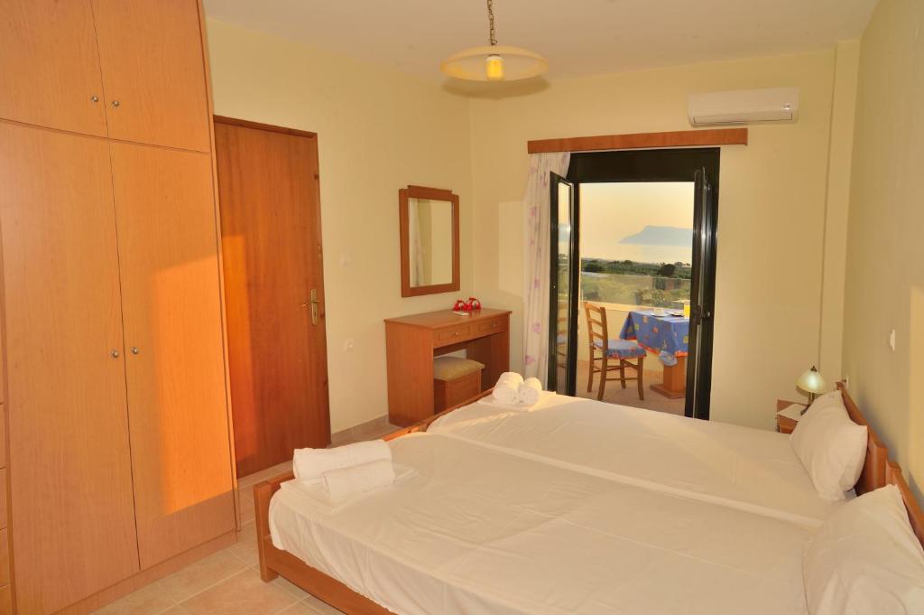 a bedroom with a white bed and a balcony at Xenios Zeus Apartments in Kissamos