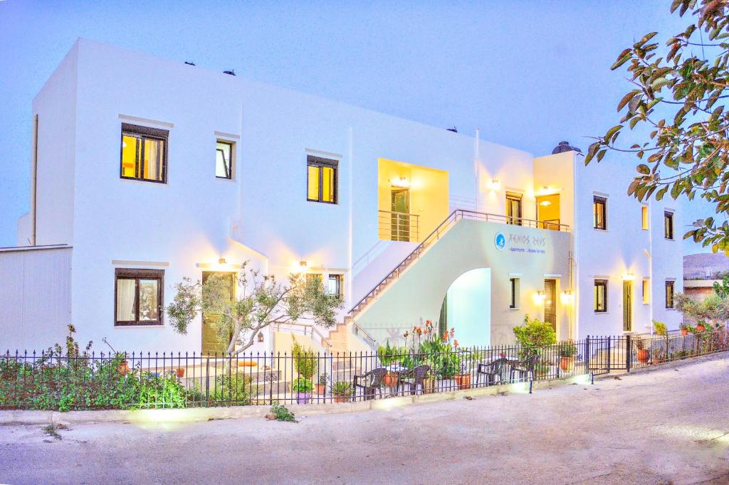 a white building with a fence in front of it at Xenios Zeus Apartments in Kissamos