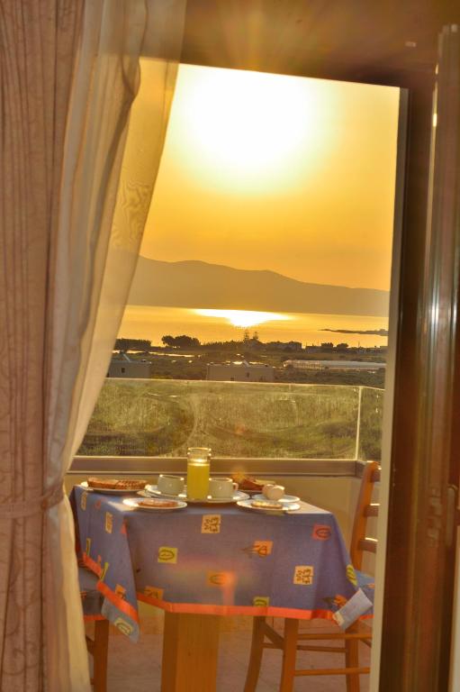 a table with a view of the sunset from a window at Xenios Zeus Apartments in Kissamos