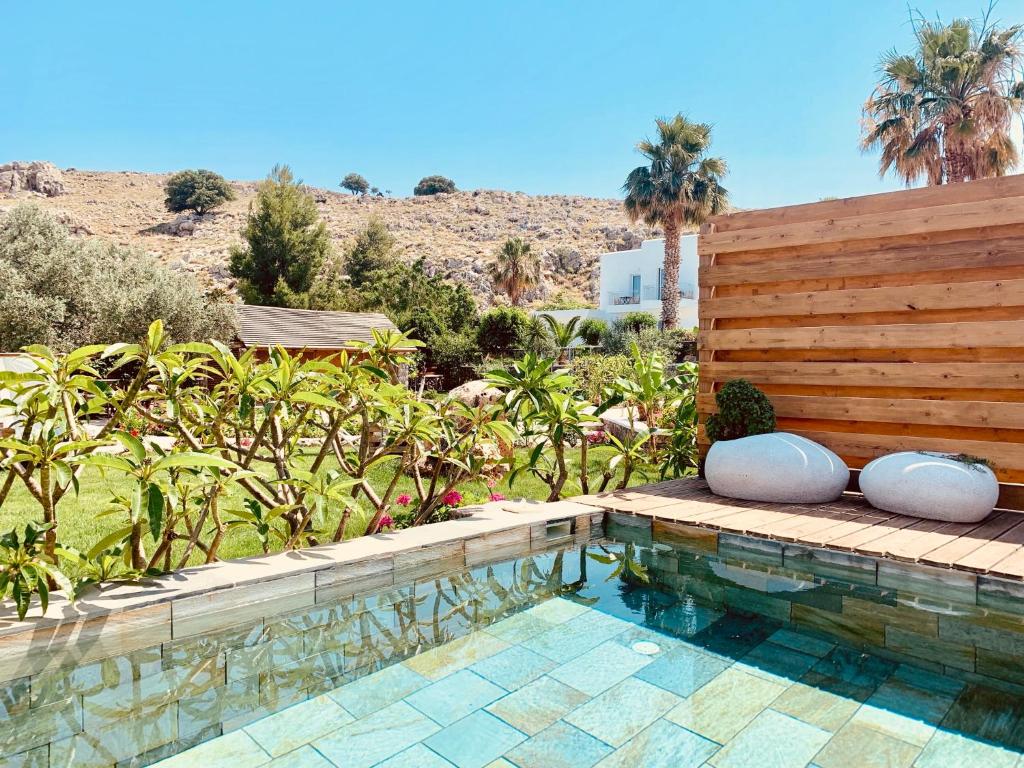 a pool with two pillows next to a wooden fence at Caesars Gardens Hotel & Spa - Adults Only in Lindos