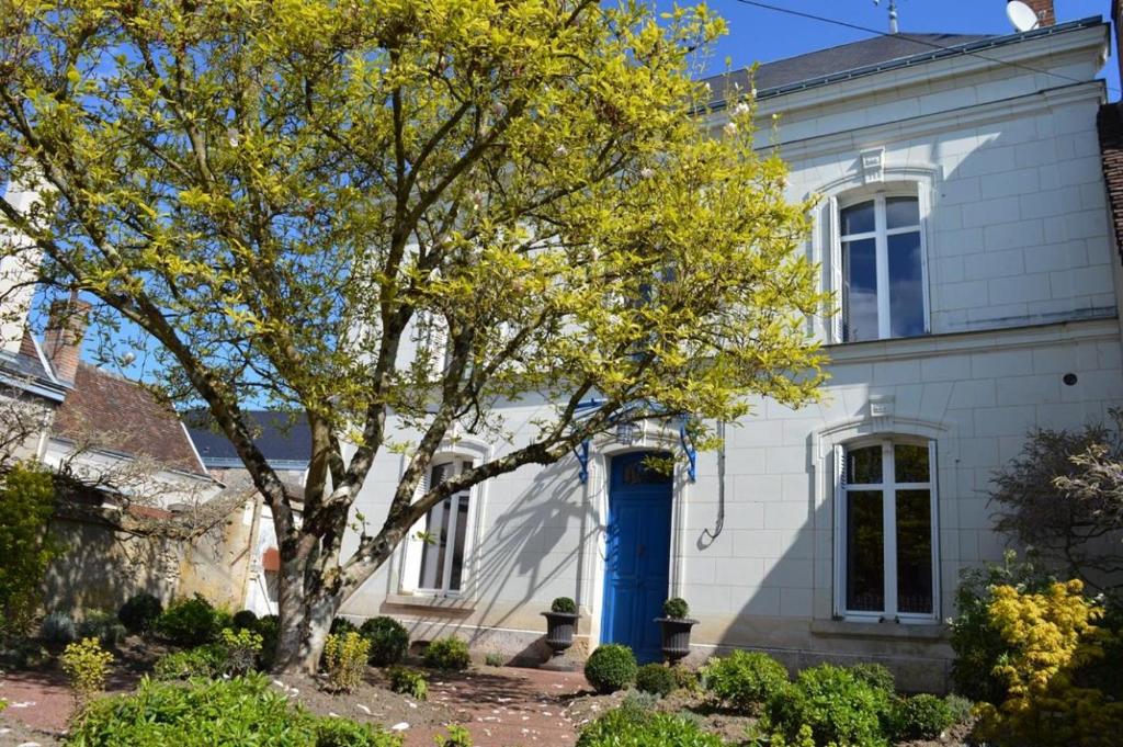 un albero davanti a una casa bianca con una porta blu di Le MAGNOLIA a La Croix-en-Touraine