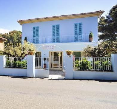 ein weißes Haus mit einem Tor und einer Tür in der Unterkunft Guerrini Hotel in Castiglioncello