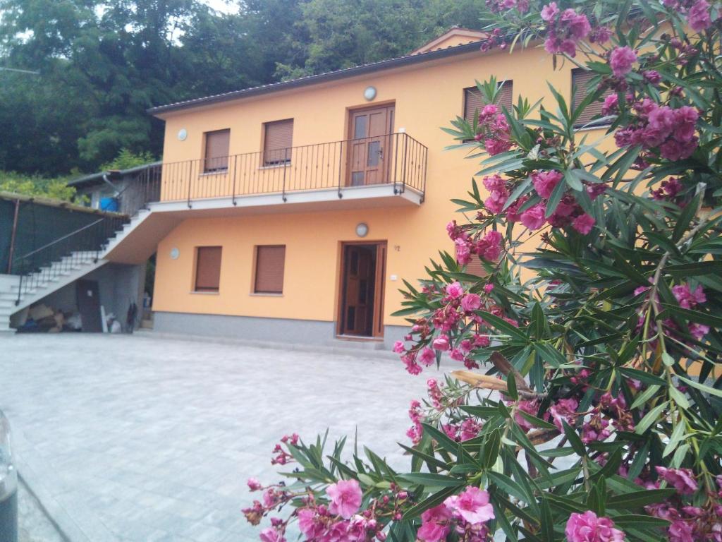een groot geel huis met een balkon en roze bloemen bij APARTMAJI MATAŽIN in Črni Kal