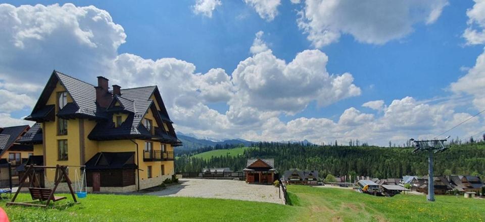 uma grande casa amarela com um parque infantil num campo em Pokoje Gościnne Stanek em Małe Ciche