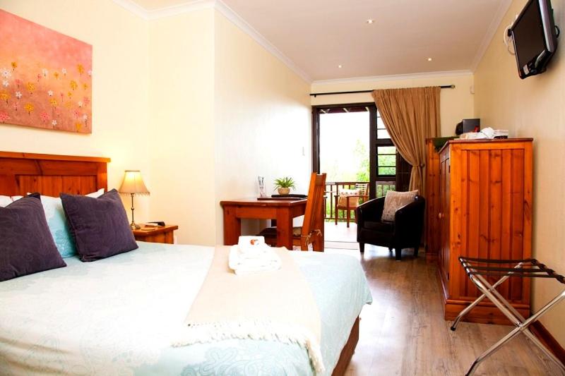 Un dormitorio con una cama, un escritorio y un televisor. en WarmKaros Bed & Breakfast, en East London