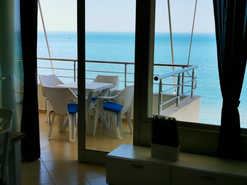 a balcony with a table and chairs and the ocean at Matin Apartment Sea View in Durrës