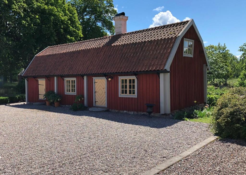 un granero rojo con una entrada de grava en Old Wing, en Enköping