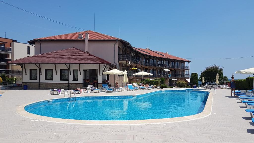 a swimming pool with chairs and umbrellas next to a building at Briz MK Apartment in Ravda