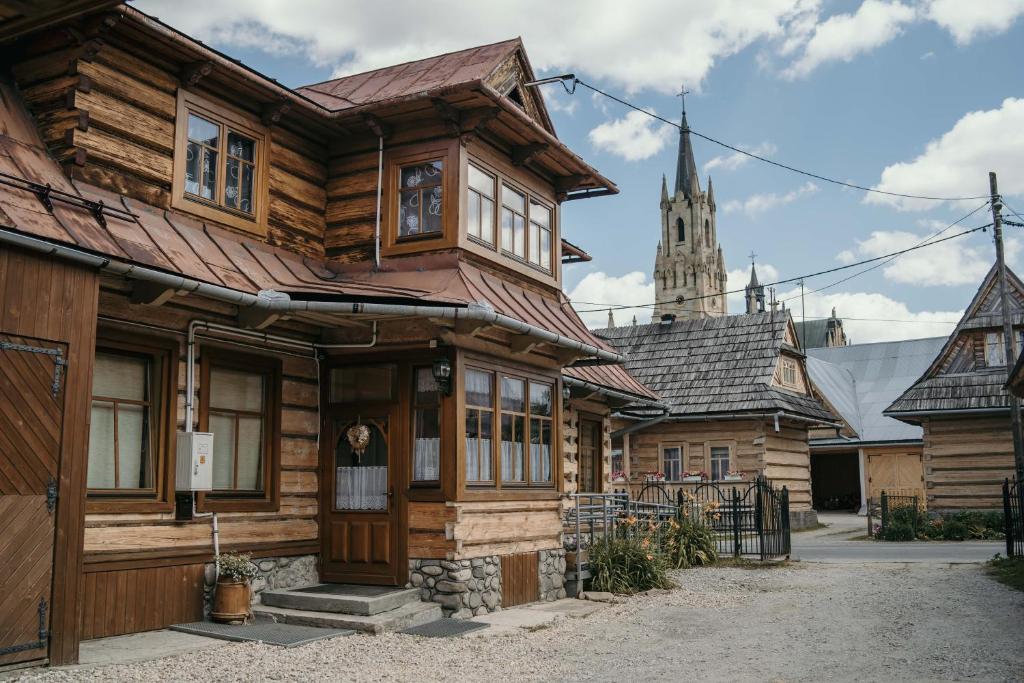 a wooden house with a church in the background at Apartament we Wsi in Chochołów