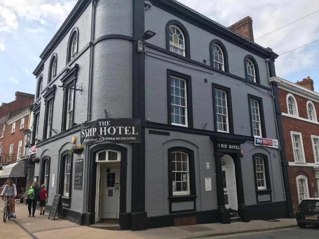 Ein schwarzes Gebäude auf einer Stadtstraße mit Leuten, die laufen. in der Unterkunft The Ship Hotel in Crediton