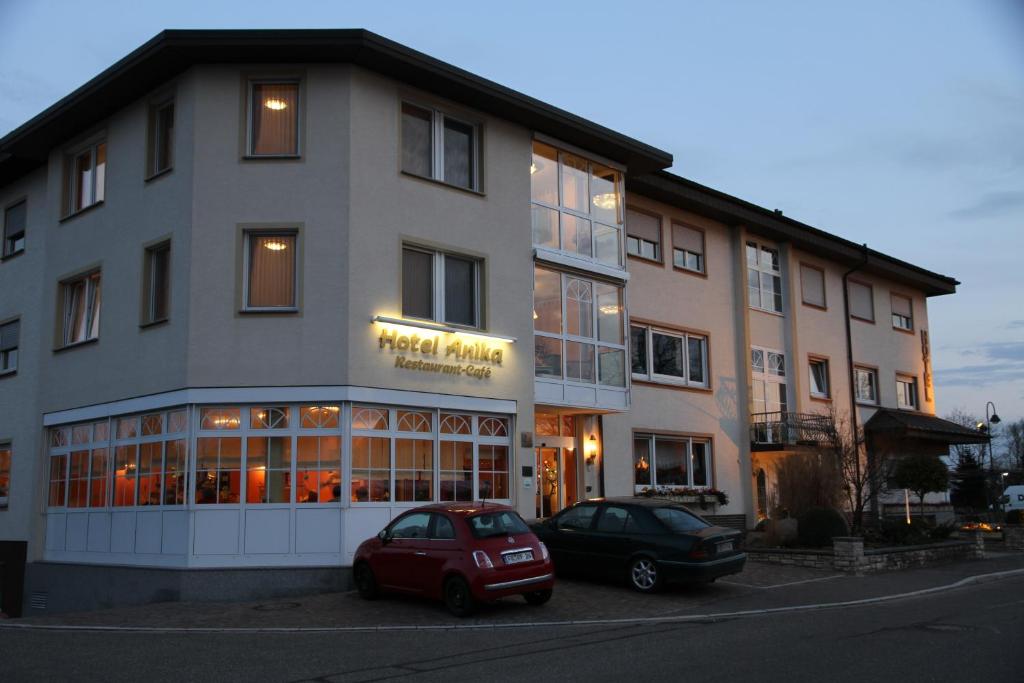 une voiture rouge garée devant un bâtiment dans l'établissement Hotel Anika, à Neuenburg am Rhein