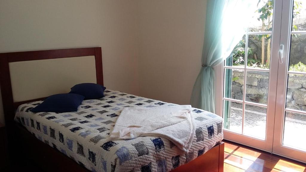 a bedroom with a bed with blue pillows and a window at Casa Shalom in Faial