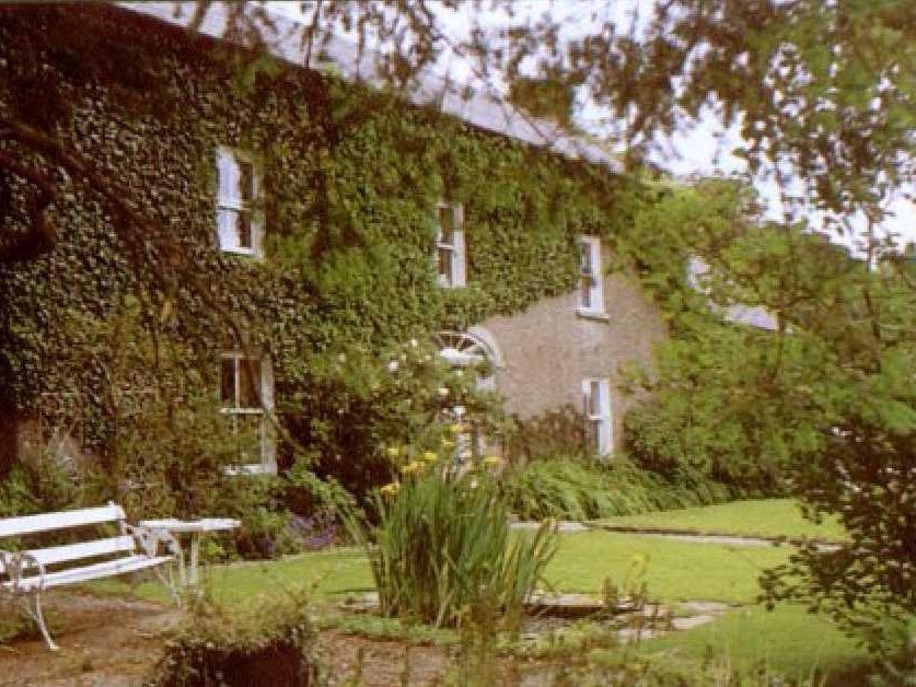 un edificio ricoperto di edera con una panca di fronte di Cullintra House a Inistioge