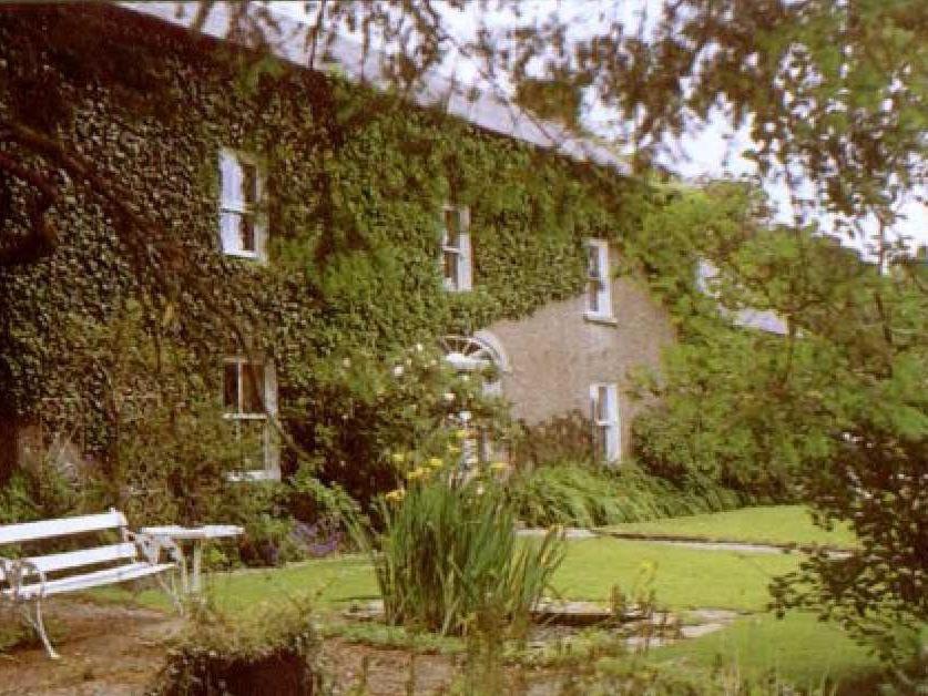 a building covered in ivy with a bench in front of it at Cullintra House in Inistioge