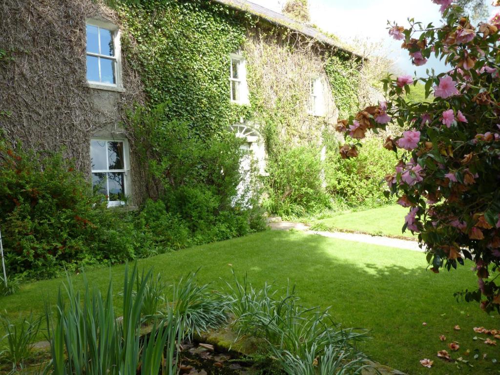 una casa ricoperta di edera con un prato di fronte di Cullintra House a Inistioge